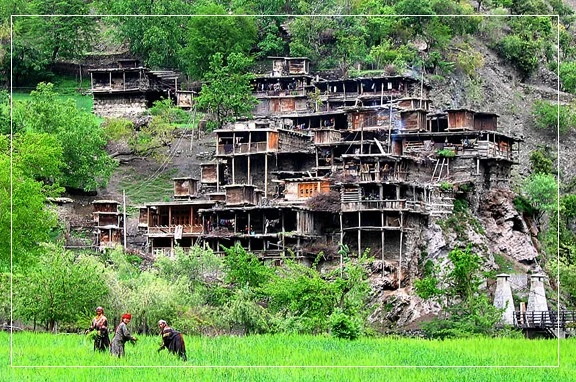 Kalash Women working in the fields, with their village in the background